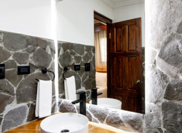 "Baño de la habitación El Salto con paredes de piedra natural y diseño elegante en Los Abetos"