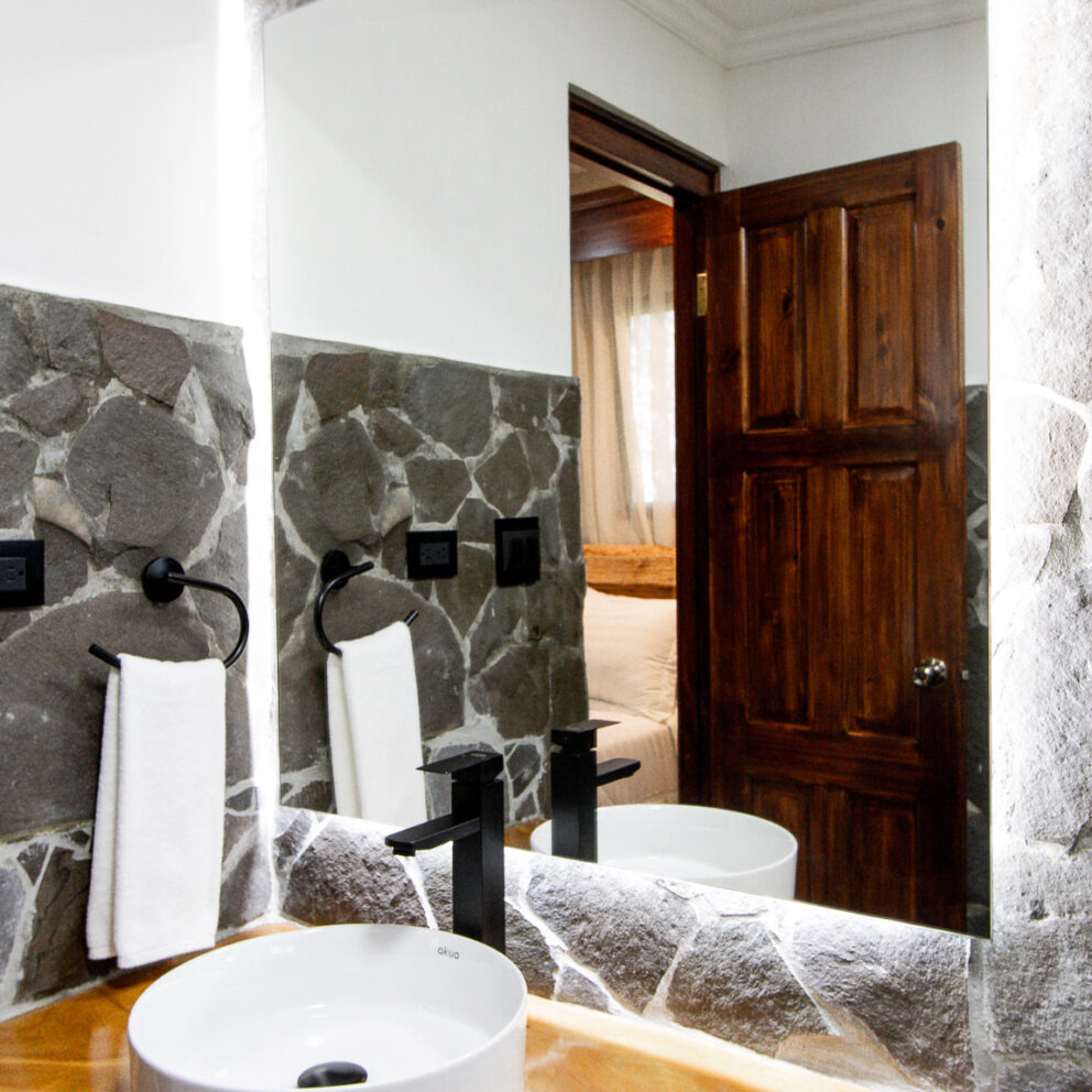 "Baño de la habitación El Salto con paredes de piedra natural y diseño elegante en Los Abetos"