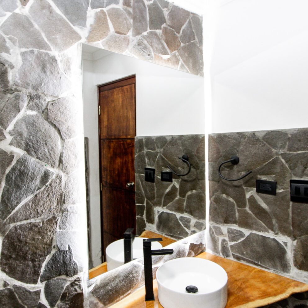 Amplio baño de la Habitación Bajo Mono combina elegancia rústica con detalles modernos. Con paredes de piedra natural y acabados en madera, este baño ofrece un ambiente cálido y acogedor, ideal para relajarse después de un día de aventuras.