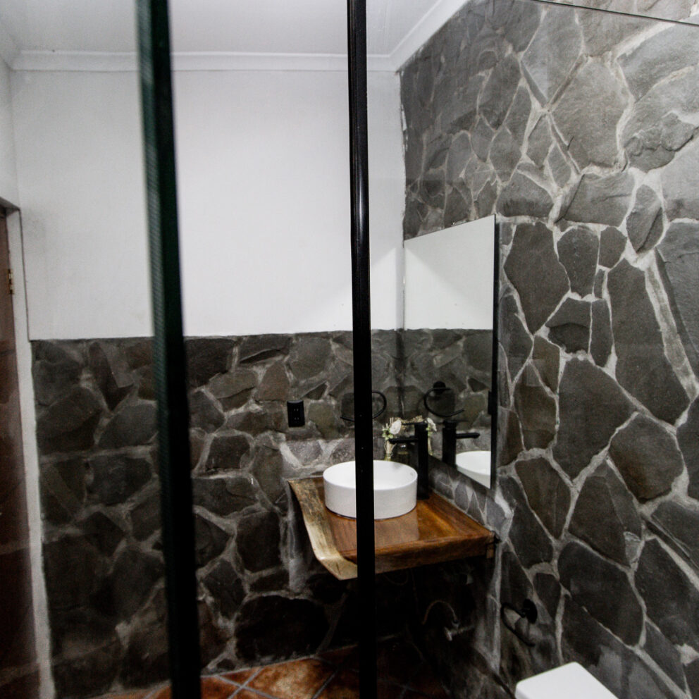 "Elegante Baño con Paredes de Piedra y Diseño Contemporáneo"